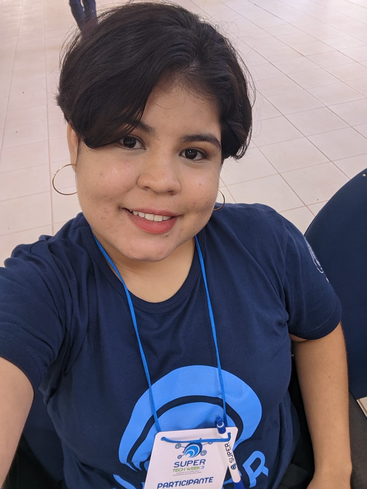 foto da Millena, sentada de cabelo curto, blusa azul e sorrindo